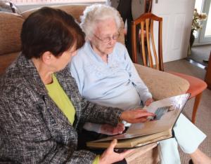 Marj Parfitt of Wightcare showing Norma Williams an album of press cuttings featuring Wightcare's work over the years
